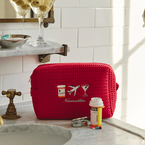 Red toiletry bag with embroidered design on a bathroom counter
