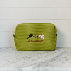 Green textured pouch with embroidered design on a marble surface