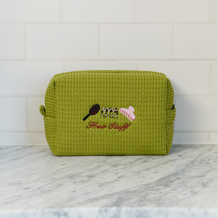 Green textured pouch with embroidered design on a marble surface