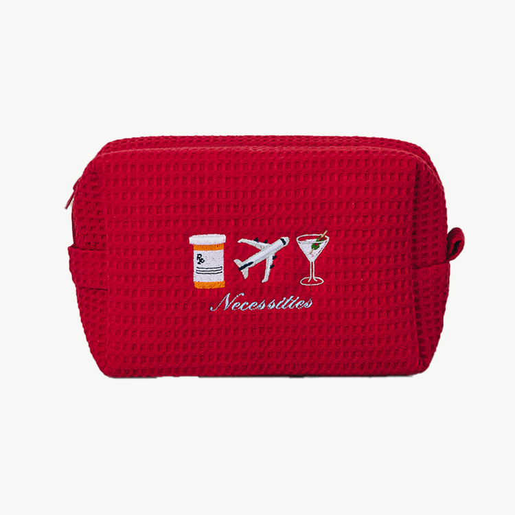Red toiletry bag with travel-themed illustrations on a white background