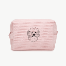 A light pink waffle zippered pouch with a black line drawing of a dogs face on the front.