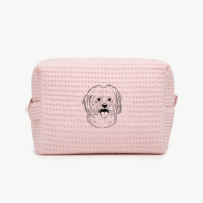 A light pink waffle zippered pouch with a black line drawing of a dogs face on the front.