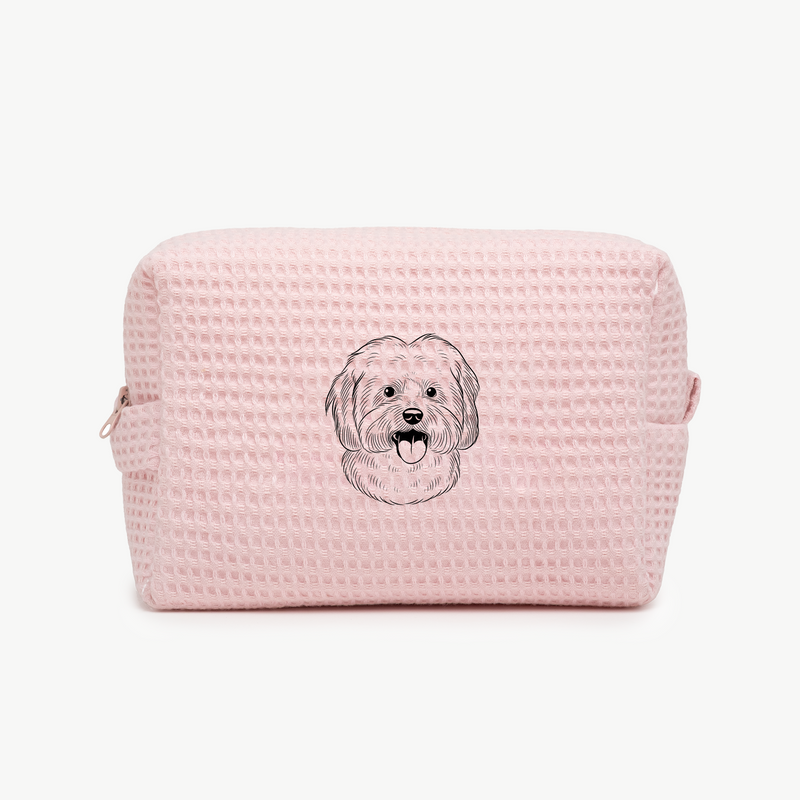 A light pink waffle zippered pouch with a black line drawing of a dogs face on the front.