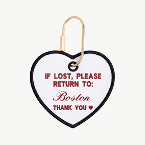 Heart-shaped tag with text 'If lost, please return to: Boston' on a white background