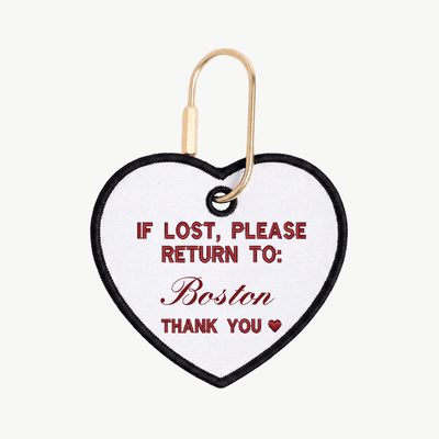 Heart-shaped tag with text 'If lost, please return to: Boston' on a white background