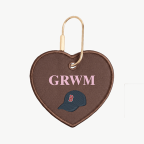 Heart-shaped keychain with 'GRWM' and a logo on a white background