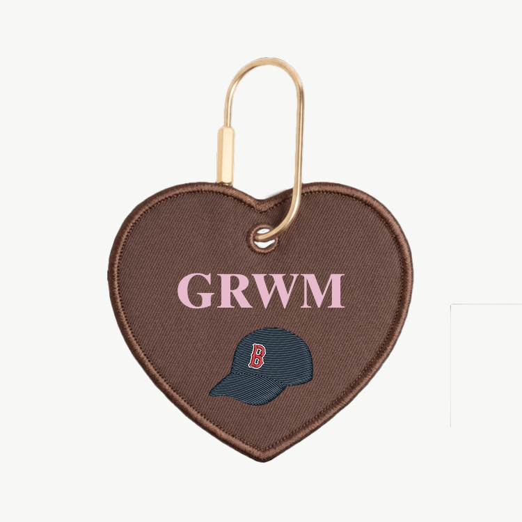 Heart-shaped keychain with 'GRWM' and a logo on a white background