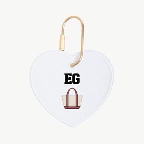 Heart-shaped keychain with 'EG' and a bag illustration on a white background