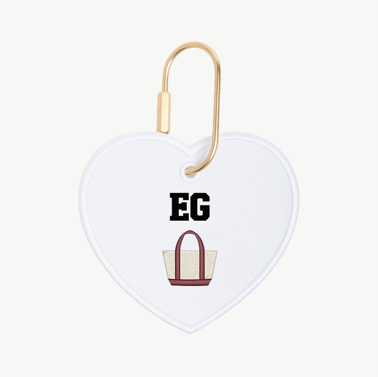 Heart-shaped keychain with 'EG' and a bag illustration on a white background