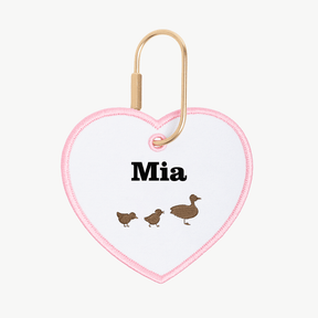 Heart-shaped keychain with 'Mia' and duck illustrations on a white background