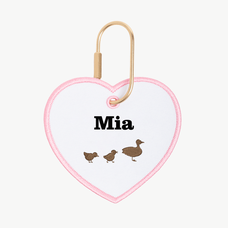 Heart-shaped keychain with 'Mia' and duck illustrations on a white background