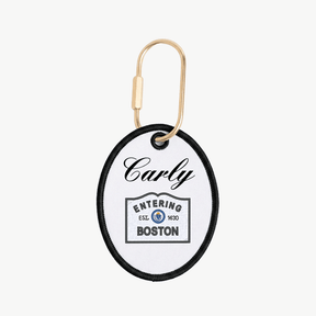 Round keychain tag with 'Carly Entering Boston' text on a white background