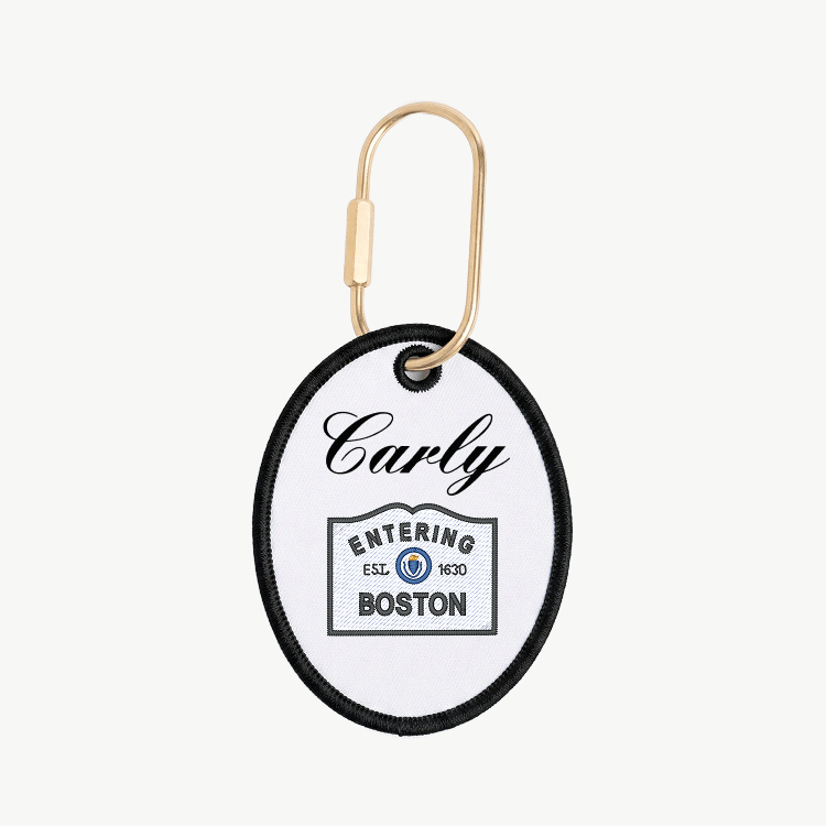 Round keychain tag with 'Carly Entering Boston' text on a white background