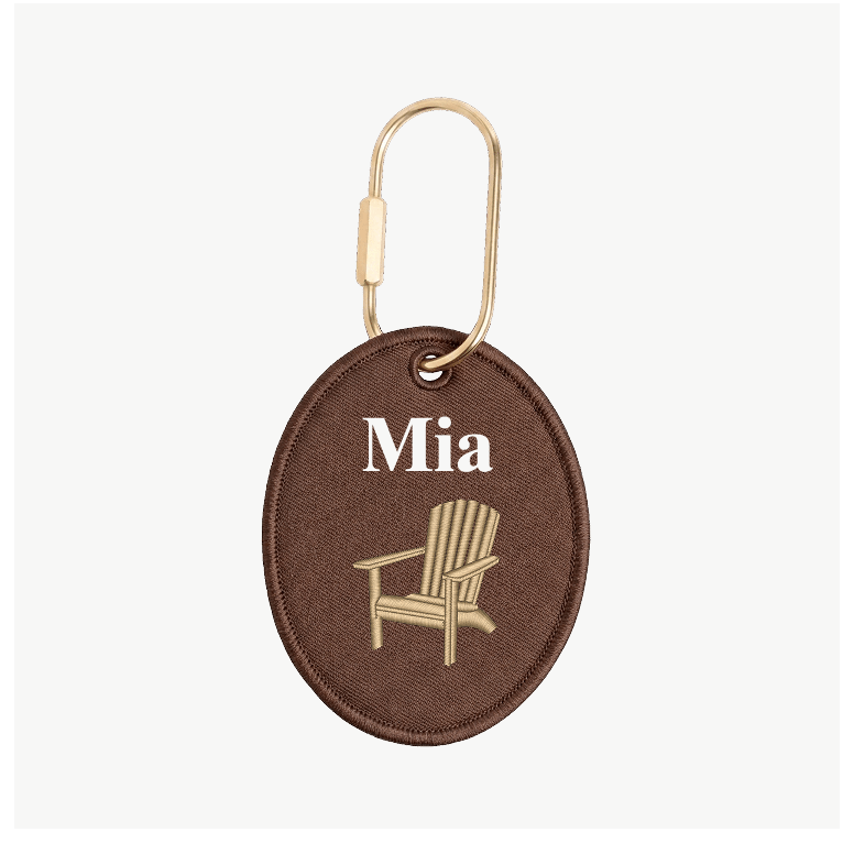 Brown keychain with 'Mia' and chair design on a white background