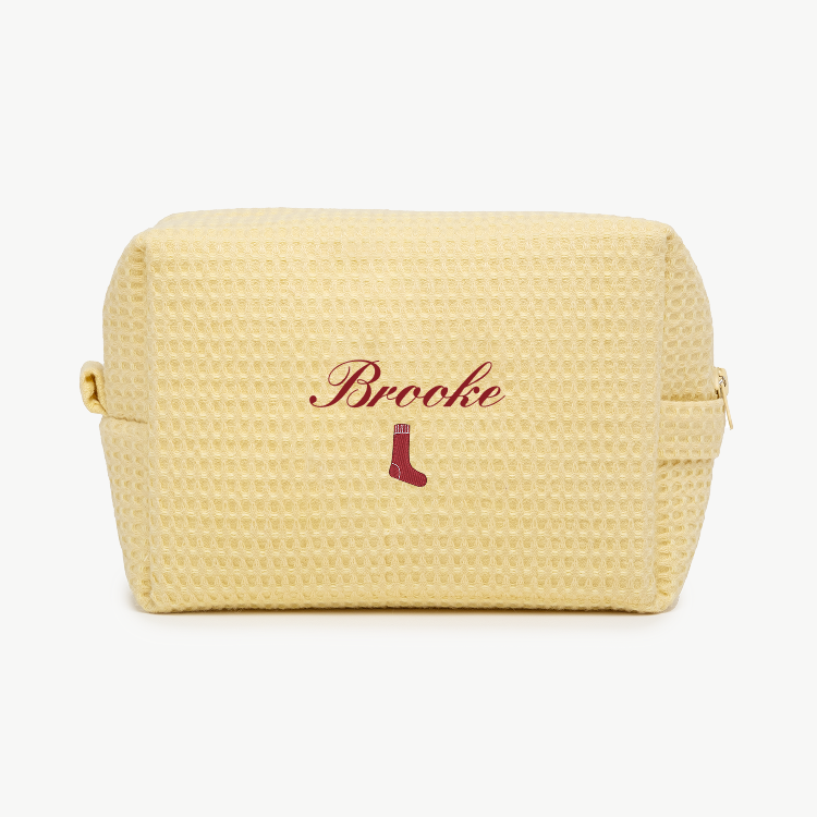 Yellow textured pouch with 'Brooke' and a sock icon on a white background