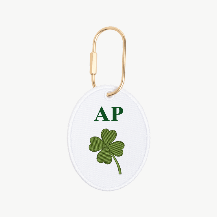 Round keychain with green four-leaf clover and 'AP' initials on a white background