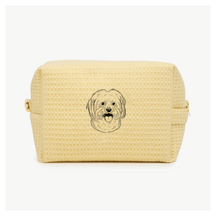 A light yellow waffle zippered pouch with a black line drawing of a dogs face on the front.