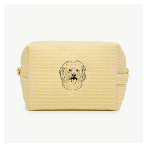 A light yellow waffle zippered pouch with a black line drawing of a dogs face on the front.