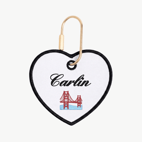 Heart-shaped keychain with 'Carlin' and a bridge design on a white background