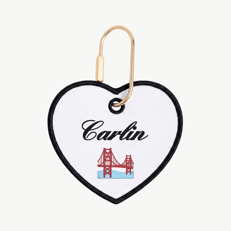 Heart-shaped keychain with 'Carlin' and a bridge design on a white background