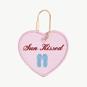 Heart-shaped keychain with 'Sun Kissed' text and flip-flop design on a pink background
