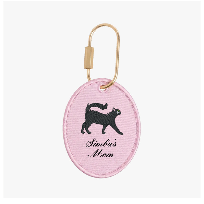 Pink keychain with black cat illustration and 'Simba's Mom' text on a white background