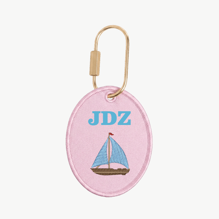 Pink oval keychain with sailboat design and 'JDZ' initials on a white background