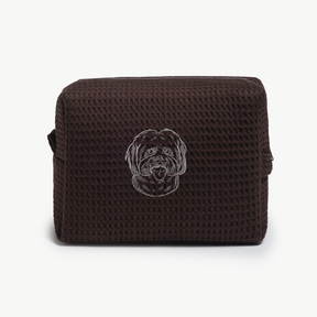 A dark brown waffle zippered pouch with a white line drawing of a dogs face on the front.