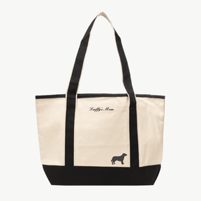 A beige canvas tote bag with long black handles and a matching black base the text 'Luffy's Mom' near the top, and a small embroidered silhouette of a dog at the bottom right.