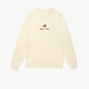 Cream crewneck sweatshirt featuring a small embroidered brown dog above the words Tyler's Mom in black script on the chest. The sweatshirt has long sleeves and a simple, relaxed design.