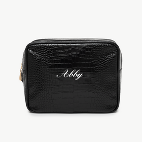 A black, croc pouch with the name Abby written in white script on the front. The background is plain white.