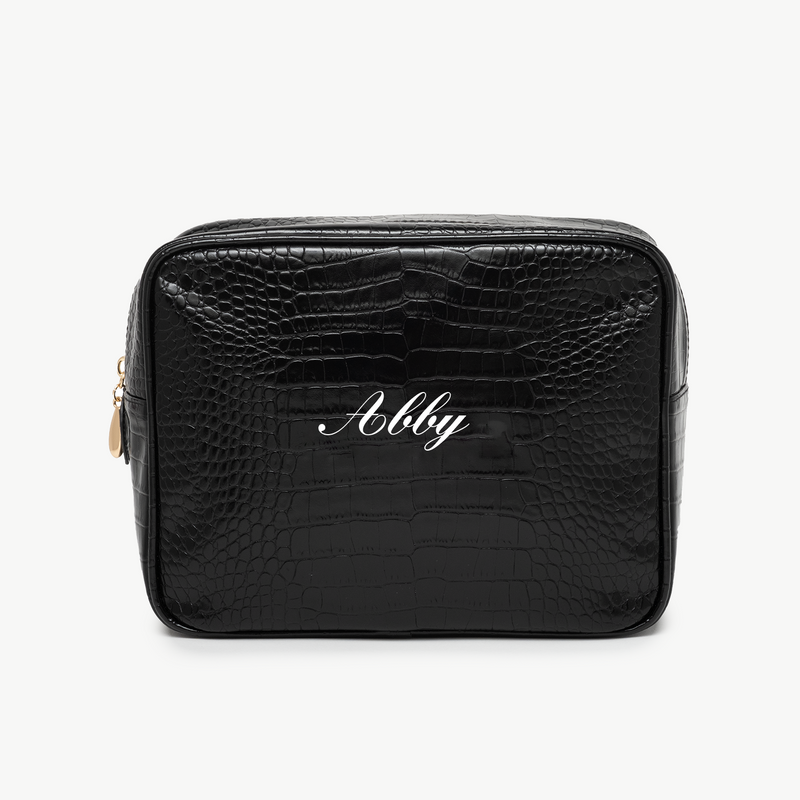 A black, croc pouch with the name Abby written in white script on the front. The background is plain white.