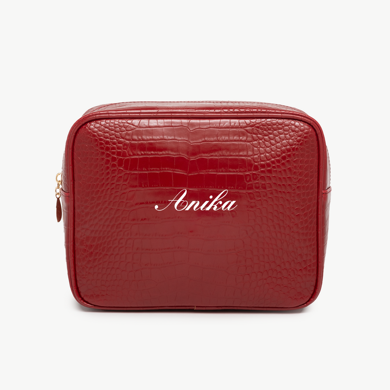 A red, croc pouch with the name Anika written in white script on the front. The background is plain white.