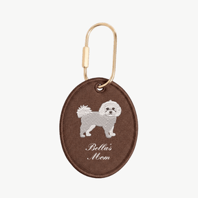 Brown oval keychain with a dog illustration and 'Bella's Mom' text on a white background