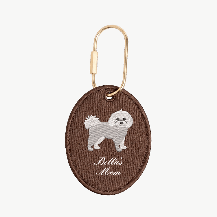 Brown oval keychain with a dog illustration and 'Bella's Mom' text on a white background