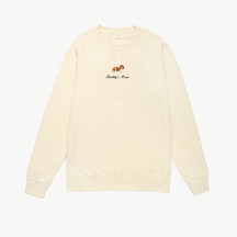 Cream crewneck sweatshirt featuring a small embroidered brown dog above the words Buddy's Mom in black script on the chest. The sweatshirt has long sleeves and a simple, relaxed design.