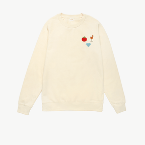 A plain cream crewneck sweatshirt with long sleeves featuring three embroidered icons of a tomato, a cocktail, and a diamond, displayed on a white background.