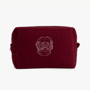 A maroon waffle zippered pouch with a white line drawing of a dogs face on the front.