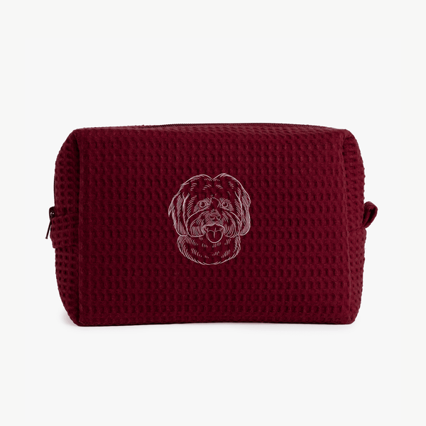 A maroon waffle zippered pouch with a white line drawing of a dogs face on the front.
