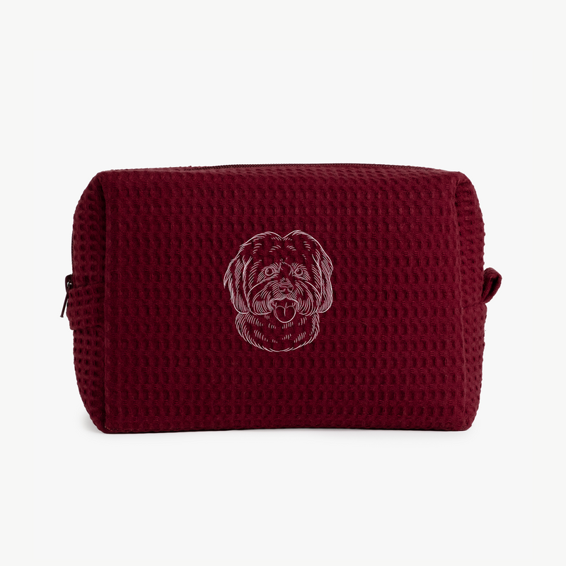 A maroon waffle zippered pouch with a white line drawing of a dogs face on the front.