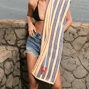 Woman holding a striped towel by the water