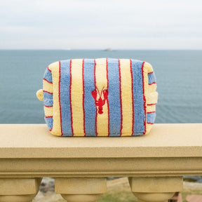 Striped pouch with a lobster design on a railing by the ocean.