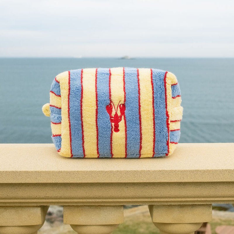 Striped pouch with a lobster design on a railing by the ocean.