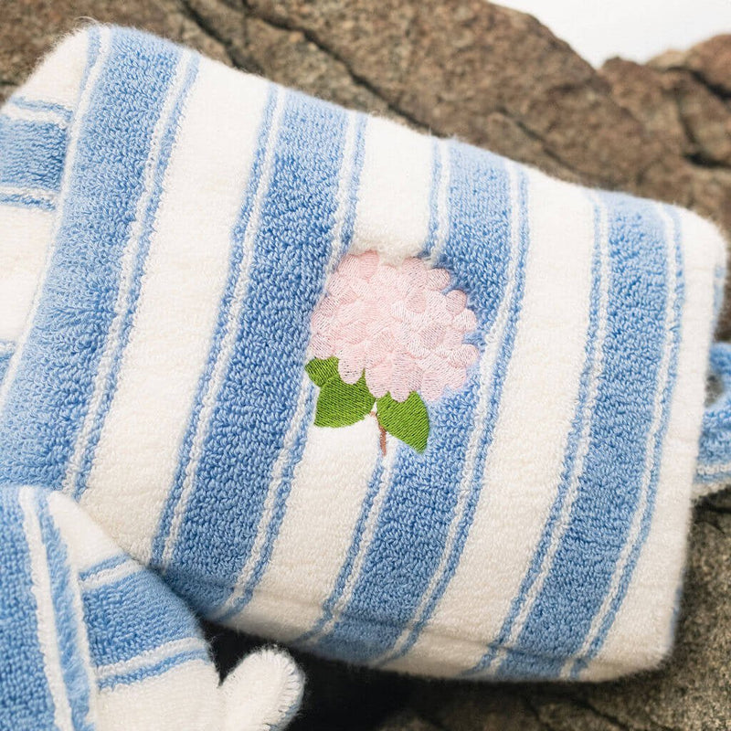 Blue and white striped pouch with a pink flower design on a stone surface