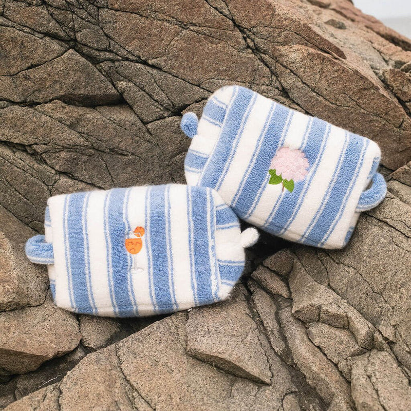 Pair of blue and white striped pouches with embroidered designs on a stone surface