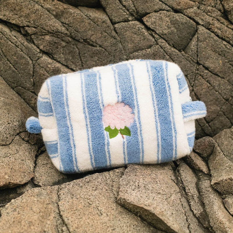 Striped fabric pouch with floral design on a textured stone surface