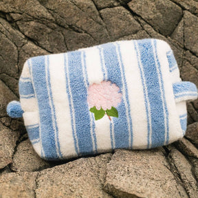 Blue and white striped pouch with a floral design on a rocky surface