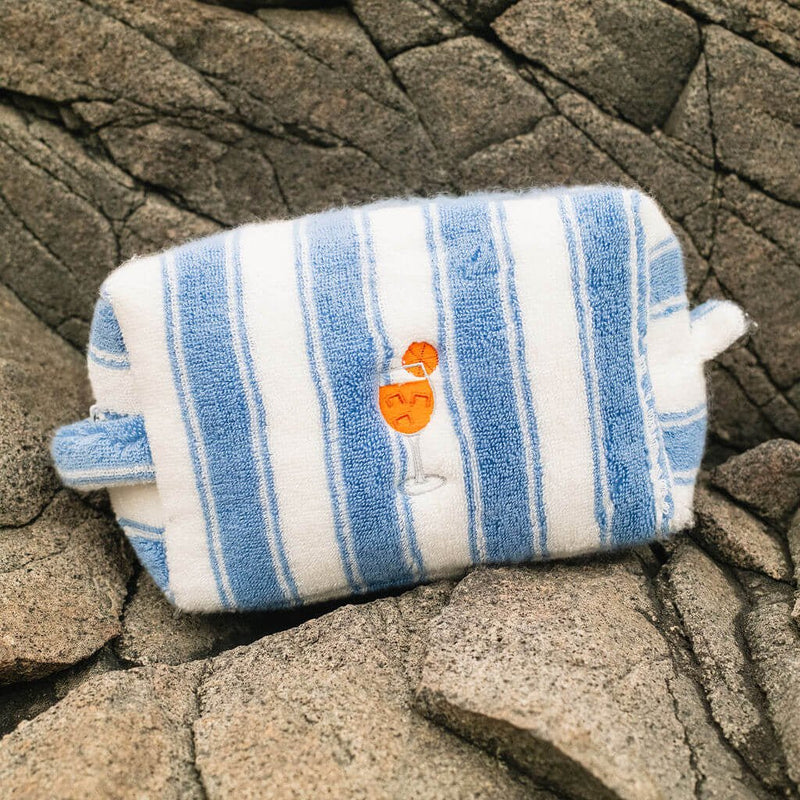 Blue and white striped pouch with a logo on a rocky surface
