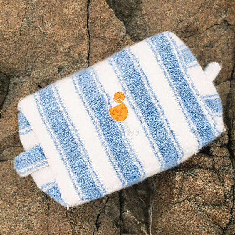 Blue and white striped pouch with a logo on a rocky surface