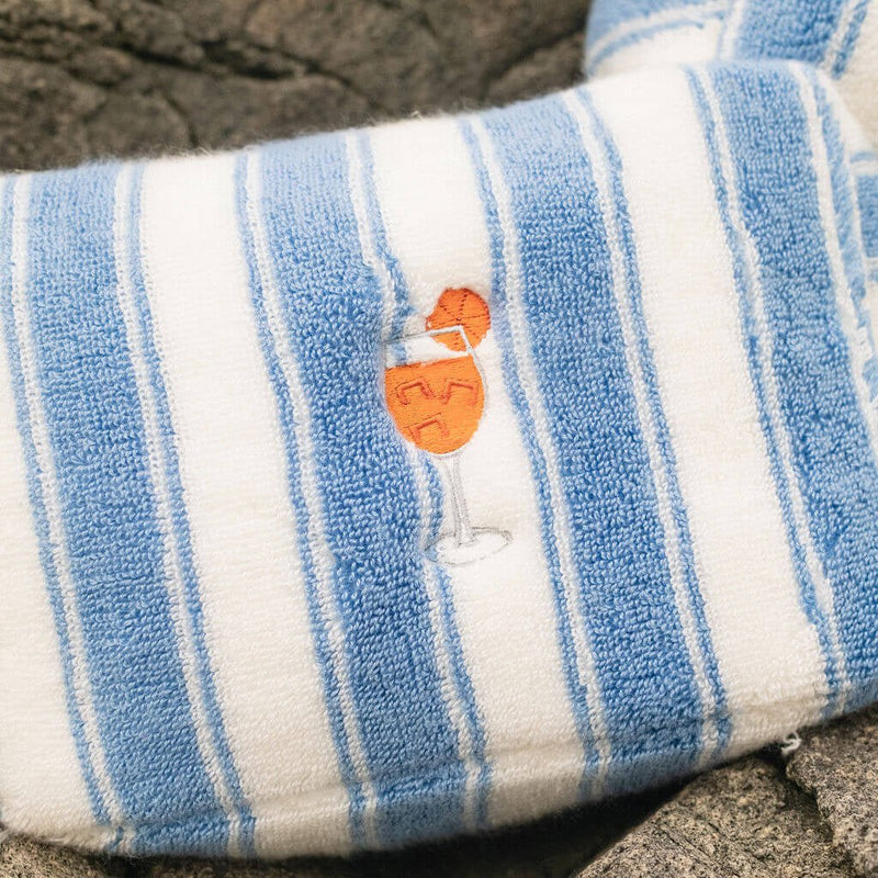 Blue and white striped pouch with a logo on a rocky surface